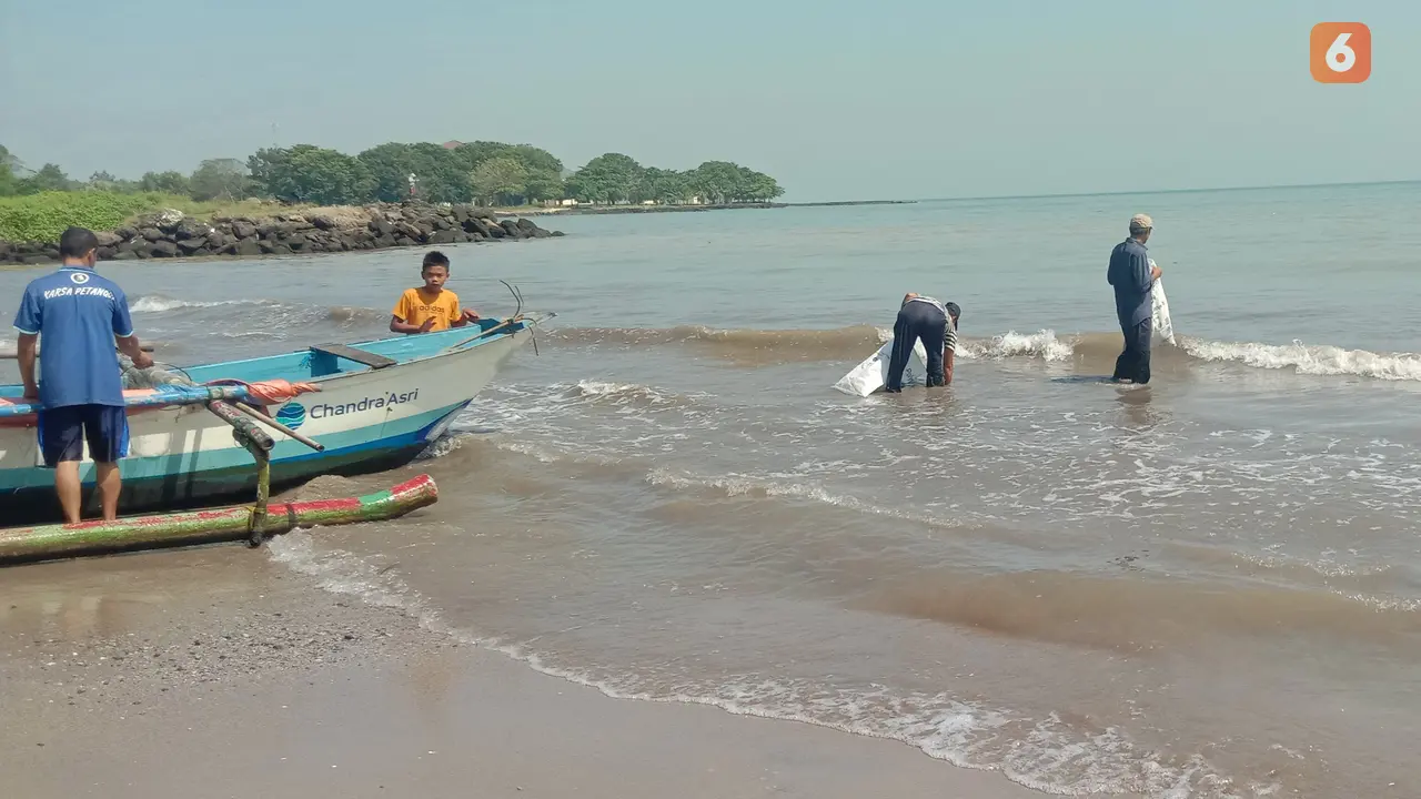 Warga Pungut Sampah Plastik Di Pantai Dan Nelayan Persiapkan Perahu Untuk Mencari Ikan Di Anyer, Kabupaten Serang, Banten. (Kamis, 30/06/2022). (Liputan6.com/Yandhi Deslatama).
