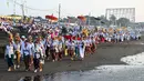 Melasti merupakan upacara adat yang bertujuan untuk menyucikan diri dan membersihkan alam dari energi negatif. Tampak dalam foto, umat Hindu saat mengikuti upacara doa Melasti di salah satu pantai di Denpasar, Bali, pada Senin 16 Maret 2026. (SONNY TUMBELAKA/AFP)