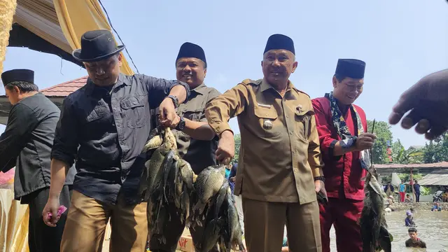 Wali Kota Depok Mohammad Idris memperlihatkan tangkapan ikan hasil ngubek empang pada rangkaian lebaran Depok, Kecamatan Bojongsari.
