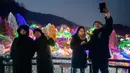 Gambar pada 11 Januari 2020, pengunjung berswafoto saat menyaksikan keindahan ribuan lampu di Garden of Morning Calm, sebelah timur Seoul di distrik Gapyeong, Korea Selatan. Festival cahaya tahunan tersebut dinikmati saat musim dingin, Desember sampai akhir bulan Maret. (Ed JONES / AFP)