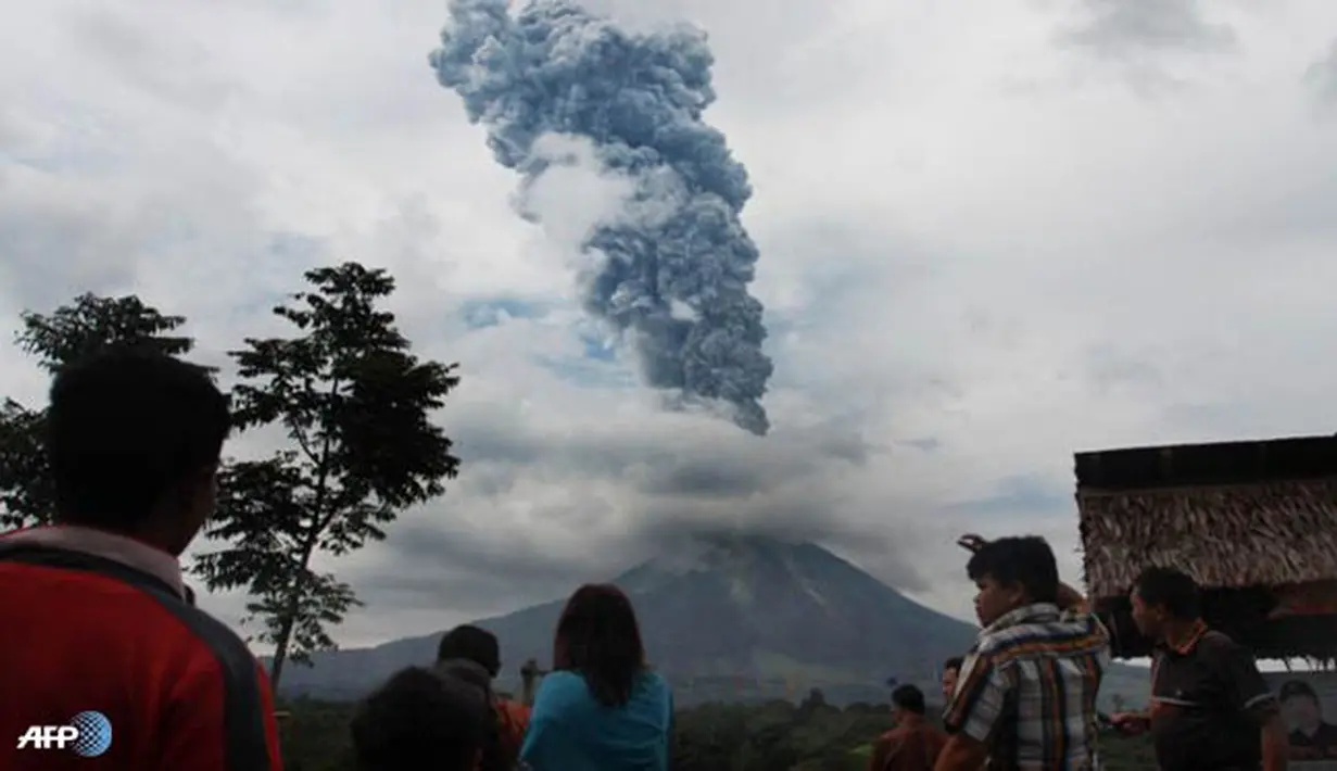 Warga menyaksikan gumpalan asap yang membumbung tinggi ke langit saat Gunung Sinabung memuntahkan uapnya. (AFP/Stringer/wwn)