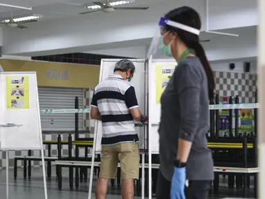 Para pemilih mengenakan masker saat memberikan suara dalam pemilu di TPS Sekolah Tinggi Chung Cheng, Singapura, Jumat (10/7/2020). Pemilu di tengah pandemi COVID-19, warga Singapura memberikan suara mereka dengan mengenakan masker dan sarung tangan plastik. (AP Photo)