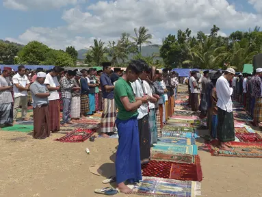 Umat muslim salat Jumat di sebuah ladang di dekat tempat penampungan sementara setelah gempa di Pemenang, Lombok (10/8). Menurut menteri senior, korban tewas akibat gempa dahsyat 6,9 SR di pulau Lombok melonjak di atas 300 orang. (AFP Photo/Adek Berry)
