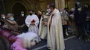 Pendeta Cesar Magana (tengah) memberkati hewan dan pemiliknya saat pesta Santo Antonius di Pamplona, Spanyol, 17 Januari 2022. Pesta santo pelindung hewan Spanyol ini dirayakan setiap tahun dan orang-orang membawa hewan peliharaan mereka ke gereja untuk diberkati. (AP Photo/Alvaro Barrientos)