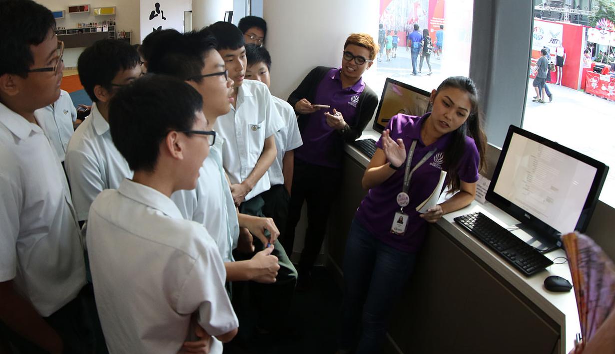 Petugas memberikan penjelasan kepada pengunjung tentang koleksi ribuan buku di Perpustakaan Olah Raga Singapura yang terletak di Pusat Olah Raga Singapura (Singapore Sports Hub). (Bola.com/Arief Bagus)