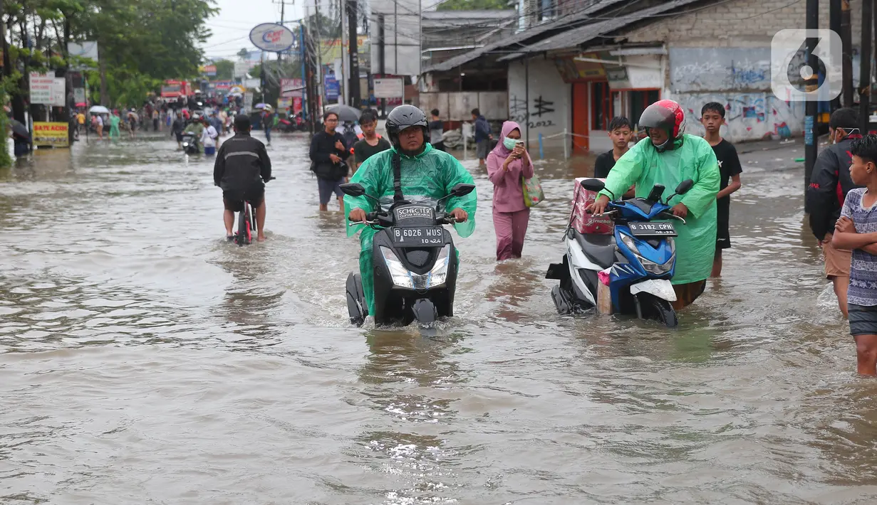 Warga berusaha melintasi genangan air ketika banjir merendam Jalan KH. Hasyim Ashari, Tangerang, Banten, Sabtu (16/7/2022). Akibat luapan kali angke ruas jalan yang menghubungkan Tangerang-Jakarta itu terputus akibat banjir. (Liputan6.com/Angga Yuniar)