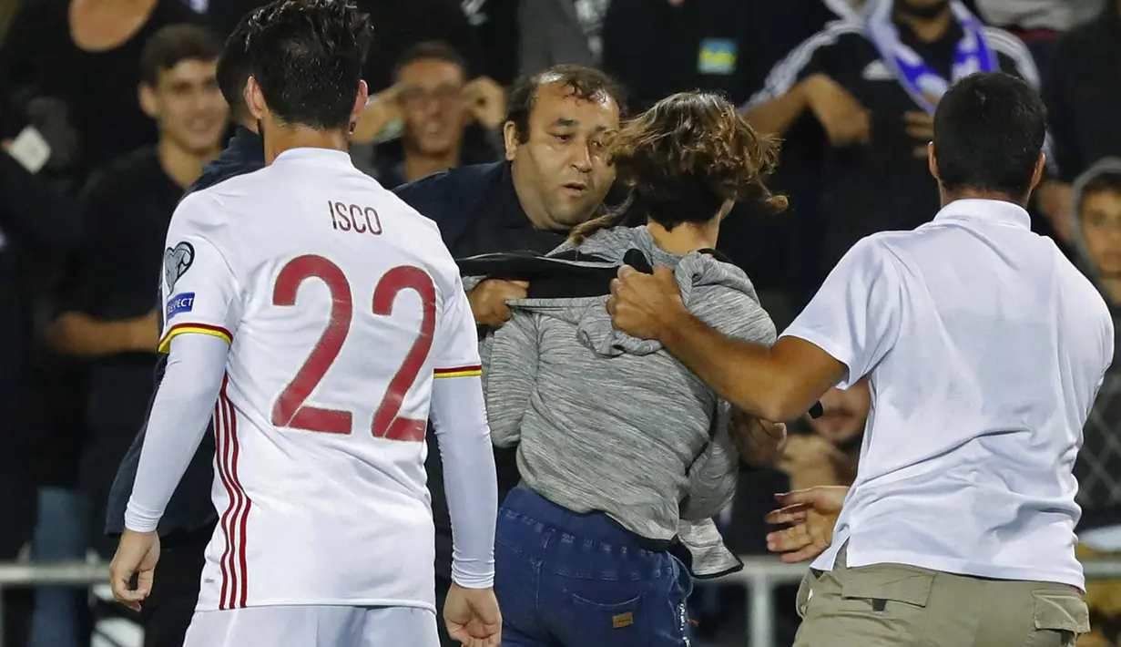 Petugas membawa pria yang mendekati Isco saat pertandingan Israel melawan Spanyol di Stadion Teddy di Yerusalem (9/10). Para suporter digelandang akibat masuk lapangan usai laga pertandingan. (AFP Photo/Jack Dan Jack Guez)