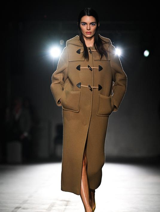 Kendall Jenner berjalan di catwalk saatmempersembahkan kreasi Prada selama Koleksi Wanita Musim Gugur-Musim Dingin 2023-2024 sebagai bagian dari Fashion Week di Milan pada 23 Februari 2023. Kendaall menambahkan beberapa inci ekstra tinggi ke bingkai patungnya dengan sepasang tumit gaya origami kuning keemasan yang unik, dihiasi dengan bunga. (AFP/Marco Bertorello)
