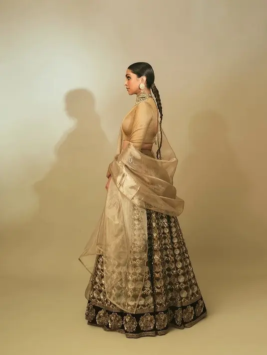 Deepika Padukone, mengenakan atasan crop top lengan panjang dari warna emas karya Sabyasachi. Dengan rok hitam berbordir emas memukau. [@deepikapadukone]