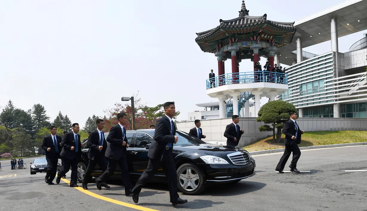 Para pengawal berlari di samping mobil yang membawa Pemimpin Korea Utara Kim Jong-un saat akan makan siang dalam KTT Korea Selatan-Korea Utara di zona demiliterisasi, Panmunjom, Korea Selatan, Jumat (27/4). (Korea Summit Press Pool/AP)
