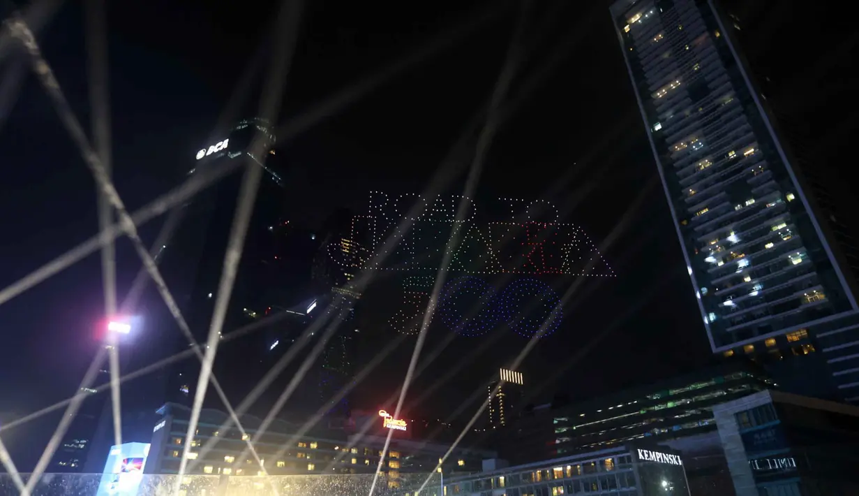 Formasi drone terlihat tepat berada di atas panggung utama perayaan tahun baru. Tampak dalam foto, warga mengabadikan pertunjukan drone saat perayaan malam pergantian tahun di kawasan Bundaran Hotel Indonesia, Jakarta, Rabu (31/12/2025). (Kapanlagi.com/Budy Santoso)