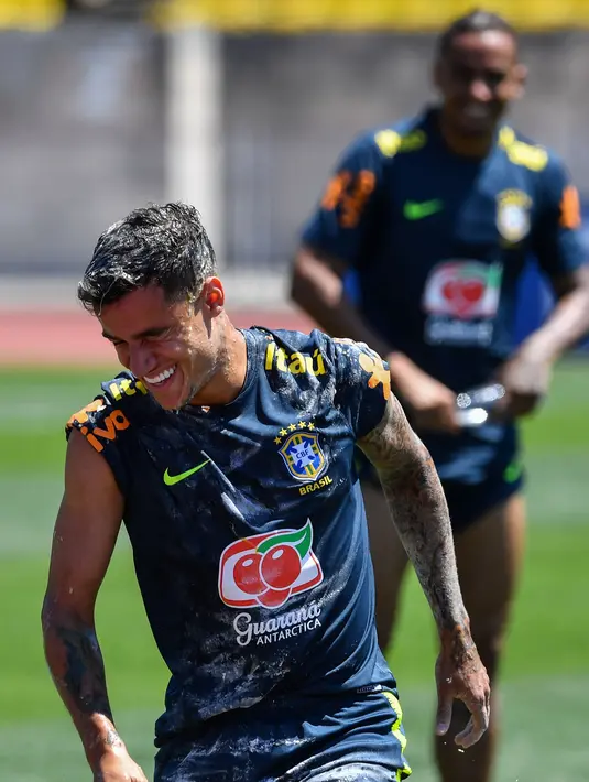 Tawa pemain sepak bola Brasil, Coutinho (kiri) saat diceploki telur dan tepung oleh rekan-rekannya dalam sesi latihan jelang Piala Dunia 2018 di Sochi, Rusia, Selasa (12/6). (Nelson Almeida/AFP)