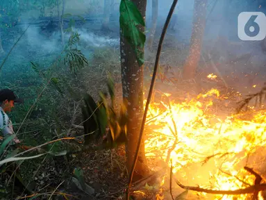 Petugas keamanan memadamkam api yang membakar lahan hutan kota di kawasan Perumahan Batan Indah, Tangerang Selatan, Banten, Senin (9/10/2023). (merdeka.com/Arie Basuki)