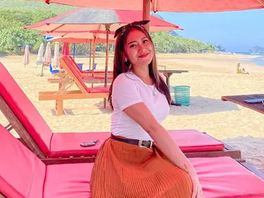 Vita Alvia sering kali mengunggah momen liburan di akun Instagram pribadinya. Penyanyi yang berasal dari Banyuwangi tersebut kerap berlibur ke pantai. Penampilannya dengan baju putih dan rok panjang berwarna oranye, ia tampak bahagia bersantai di kursi pantai. (liputan6.com/IG/@iam_vitaalvia)