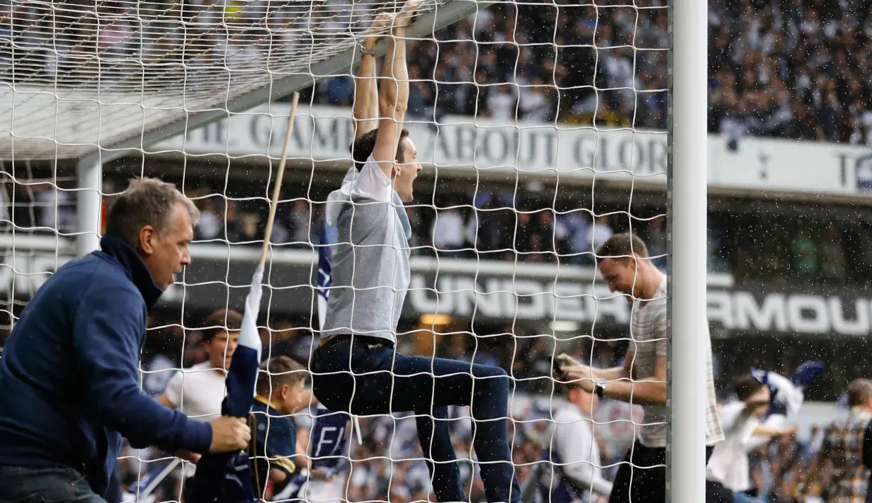 Seorang supporter Tottenham Hotspur bergelantungan di tiang gawang usai pertandigan Tottenham Hotspur melawan MU di stadion White Hart Lane, London, (14/5). Dalam pertandingan ini Tottenham menang 2-1 atas MU. (AP/Frank Augstein)  