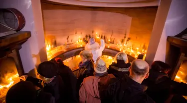 Penganut Kristen Ortodoks menyalakan llilin di gereja Saint Demetrios selama Hari Natal Ortodoks di Belgrade, Serbia (6/1). Berbeda dengan umat Kristen Protestan dan Katolik, Kristen Ortodoks merayakan natal pada tanggal 7 Januari. (AFP/Oliver Bunic)