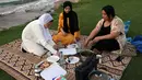 Perempuan dari Mesir dan Maroko berkumpul untuk berbuka puasa selama bulan suci Ramadhan di pantai di Muscat, Oman pada 12 April 2022. Umat islam di seluruh dunia saat ini tengah melaksanakan bulan Ramadhan dan berpuasa selama satu bulan. (MOHAMMED MAHJOUB / AFP)
