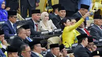 Penyanyi serta musisi, Ahmad Dhani dan Mulan Jameela saat rapat paripurna pelantikan anggota DPR Republik Indonesia terpilih periode 2024-2029 di Gedung Nusantara, Kompleks Parlemen, Senayan, Jakarta, Selasa (1/10/2024). Ahmad Dhani dan Mulan Jameela terpilih dari Partai Gerindra. Ahmad Dhani dari daerah pemilihan Jawa Timur I dengan perolehan suara sebanyak 134.227. Mulan Jameela dari daerah pemilihan Jawa Barat XI dengan perolehan suara sebanyak 83.526. (Liputan6.com/Angga Yuniar)