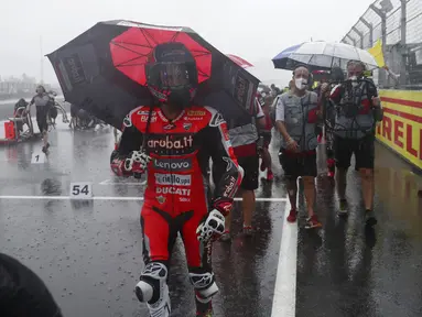 Tim mekanik dan kru kembali ke paddock saat hujan deras sebelum Race 1 World Superbike (WSBK) di Pertamina Mandalika International Street Circuit, Lombok Tengah, Nusa Tenggara Barat, Sabtu (20/11/2021). Hujan deras memaksa Race 1 WSBK Mandalika ditunda pada 21 November. (AP Photo/Achmad Ibrahim)