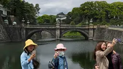 Wisatawan berswafoto dan selfie di pintu masuk utama Istana Kekaisaran di Tokyo, Jepang (29/4/2019). Kaisar Jepang Akihito akan turun dari Tahta Krisan pada 30 April 2019 mengakhiri 30 tahun masa pemerintahannya. (Kazuhiro NOGI / AFP)