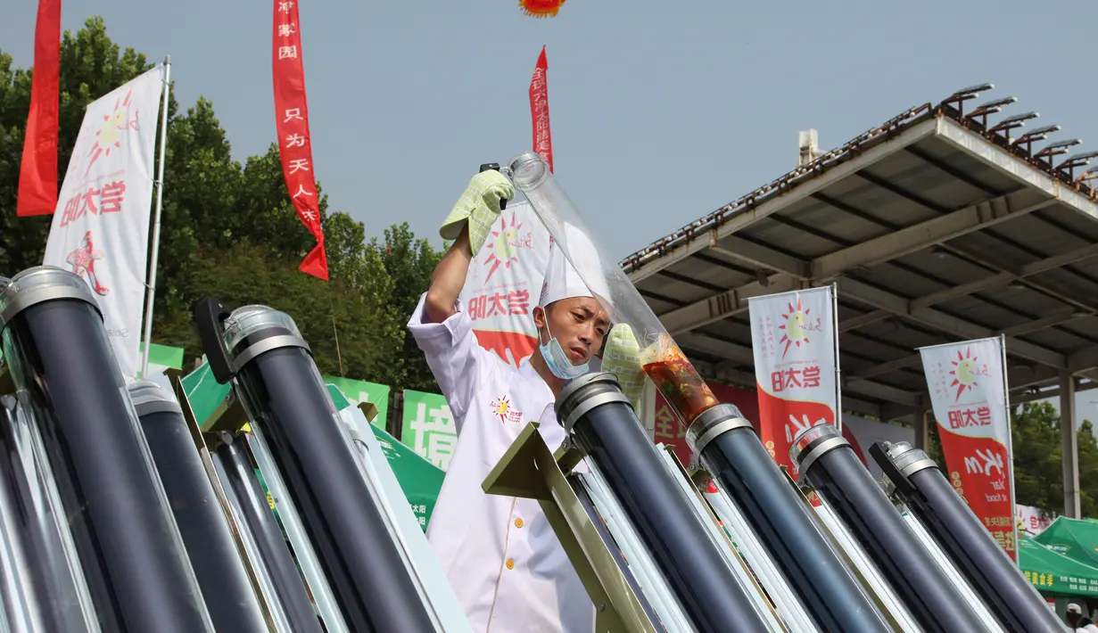 Seorang koki mempersiapkan untuk memasak makanan dengan kompor tenaga surya di Dezhou, Shandong Timur, Cina, 2 Agustus 2018. Dua lusin koki memasak pada festival masak menggunakan kompor tenaga surya di Cina. (AP Foto/Fu Ting)