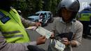 Polisi lalu lintas memeriksa kelengkapan surat pengendara saat razia Operasi Patuh Jaya 2019 di kawasan Kebon Nanas, Jakarta, Kamis (29/8/2019). Operasi ini diharapkan dapat meningkatkan kepatuhan dan ketertiban dalam berlalu lintas serta mengurangi angka kecelakaan. (merdeka.com/Imam Buhori)