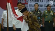 Anak pemimpin Darul Islam/Tentara Islam Indonesia (DI/TII) Sekarmaji Marijan Kartosuwiryo, Sarjono Kartosuwiryo mencium bendera Merah Putih saat pembacaan ikrar setia kepada Pancasila, UUD 45, NKRI dan Bhineka Tunggal Ika di Kemenko Polhukam, Jakarta, Selasa (13/8/2019). (merdeka.com/Imam Buhori)