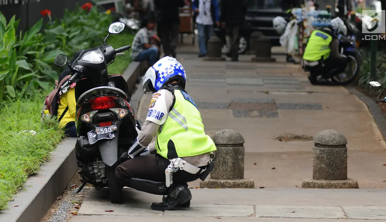 Petugas kepolisian menggembosi ban motor yang parkir di trotoar Jalan Kebon Sirih, Jakarta, Senin (17/7). Hal ini tindak lanjut maraknya pelanggaran lalu lintas di kawasan pedestrian Jalan Kebon Sirih. (Liputan6.com/Helmi Fithriansyah)