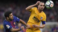 Bek Atletico Madrid, Diego Godin, duel udara dengan striker Barcelona, Luis Suarez, pada laga La Liga Spanyol di Stadion Camp Nou, Barcelona, Minggu (4/3/2018). Barcelona menang 1-0 atas Atletico. (AFP/Lluis Gene)
