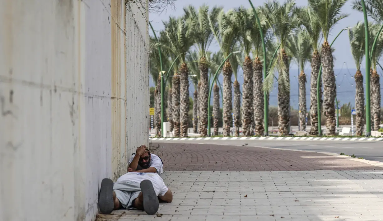 Orang-orang mencari perlindungan setelah mendengar sirene peringatan akan adanya tembakan di kota Ashkelon, Israel selatan, pada 11 Oktober 2023.  (Photo by RONALDO SCHEMIDT / AFP)