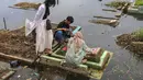 Kondisi cuaca yang kurang bersahabat dan genangan air dengan ketinggian 10 hingga 50 cm tidak menyurutkan niat untuk tetap datang ke lokasi pemakaman untuk mendoakan serta membersihkan area makam keluarga yang telah wafat. Tampak dalam foto, warga mengunjungi makam anggota keluarga mereka di Tempat Pemakaman Umum (TPU) Semper, Cilincing, Jakarta Utara pada 15 Februari 2026. (Syinatria RESPATI/AFP)