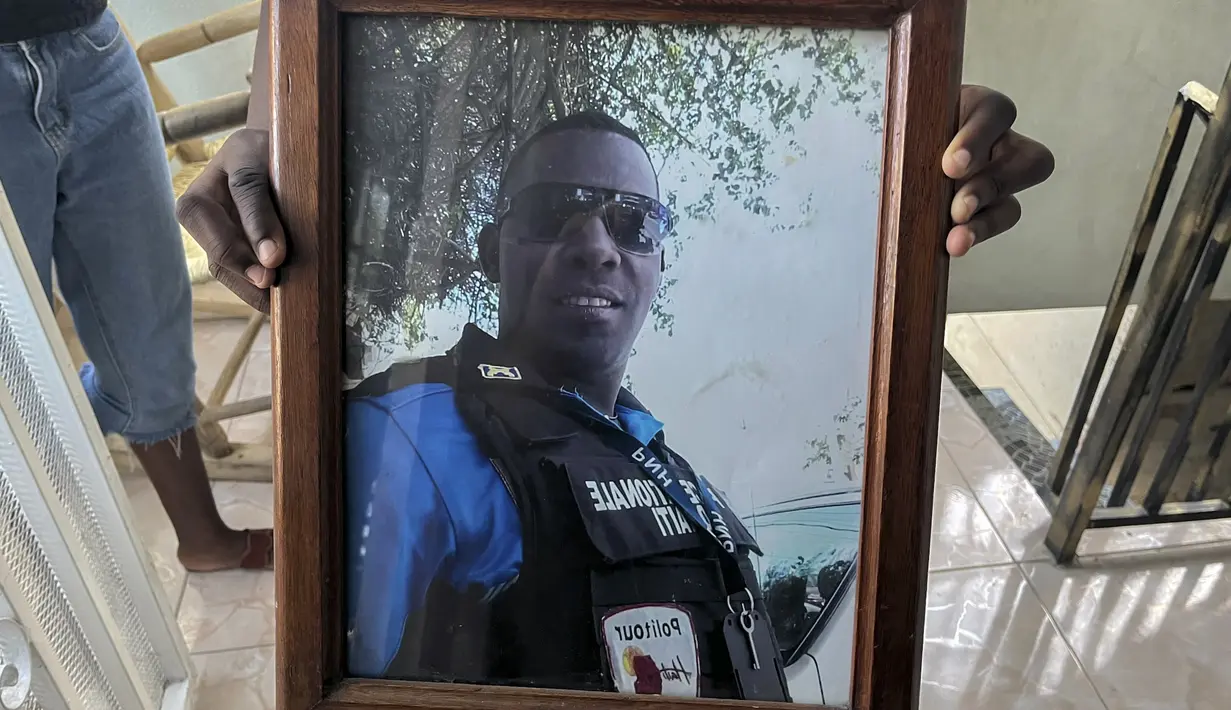Foto petugas polisi Haiti Ricken Staniclasse yang hilang dipegang oleh putranya yang berusia 11 tahun di rumah mereka di Port-au-Prince, Sabtu (21/1/2023). Haiti telah terperosok dalam krisis politik dan ekonomi selama bertahun-tahun. Akibatnya kriminalitas dan kemiskinan semakin meningkat. (AP Photo/Megan Janetsky)