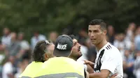 Seorang suporter berusaha memeluk penyerang Juventus, Cristiano Ronaldo selama pertandingan persahabatan antara Juventus A dan tim B, di Villar Perosa, Italia utara, (12/8). Pada pertandingan ini Ronaldo mencetak satu gol. (AFP Photo/Isabella Bonotto)