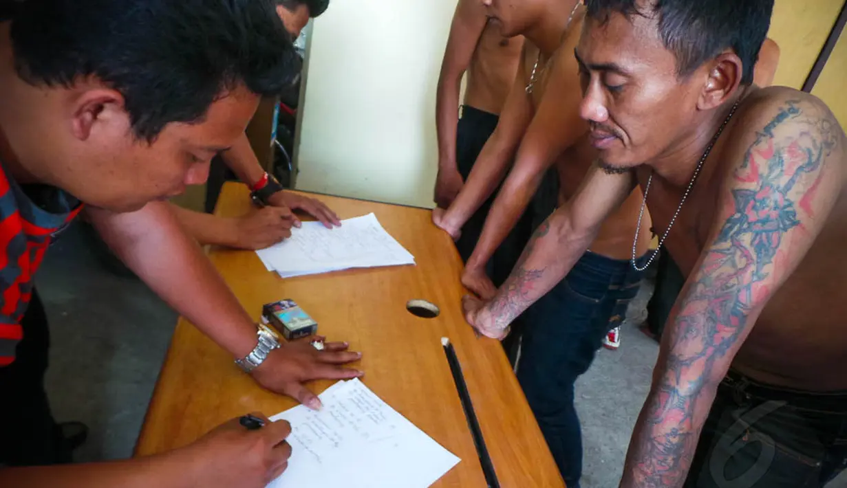 Petugas kepolisian terlihat melakukan pendataan identitas 112 preman tersebut, Jakarta, Jumat (29/8/14). (Liputan6.com/Faizal Fanani)