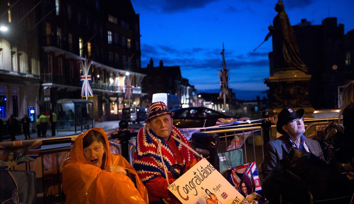 Penggemar Kerajaan Inggris duduk di luar Istana Windsor menjelang pernikahan Pangeran Harry dan Meghan Markle di Windsor, Inggris, (16/5). Pernikahan tersebut akan digelar pada 19 Mei 2018. (AP Photo / Emilio Morenatti)
