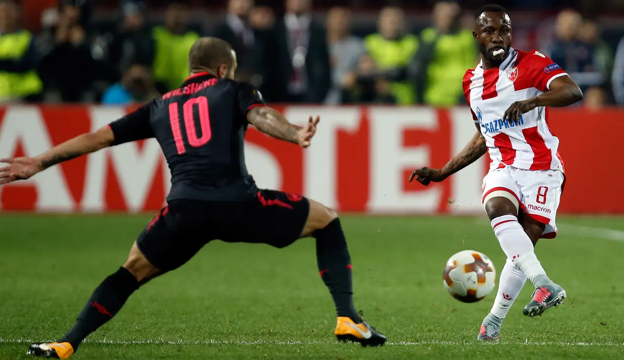 Pemain Red Star Belgrade, Guelor Kanga menendang bola yang akan direbut oleh pemain Arsenal Jack Wilshere pada pertandingan Grup H Liga Europa di Stadion Rajko Mitic, Kamis (19/10). Arsenal menang 1-0, berkat gol Olivier Giroud. (AP/Darko Vojinovic)