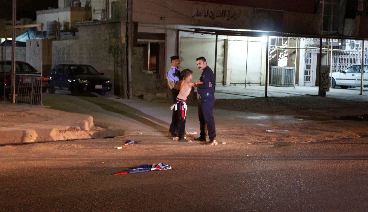 Pasukan keamanan Irak mengeledah seorang bocah  yang membawa bom di Kirkuk, Irak, (21/8). Bocah ini menangis saat diamankan oleh petugas keamanan. (REUTERS/Ako Rasheed)