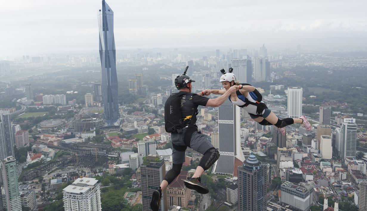 Sepasang pelompat BASE terjun dari Menara Kuala Lumpur selama KL Tower International Jump Malaysia di Kuala Lumpur, Jumat (3/2/2023). Ada yang melompat dengan santai tapi banyak juga yang berpose lucu sambil melompat, bahkan salto selama terjun bebas. (AP Photo/Vincent Thian)