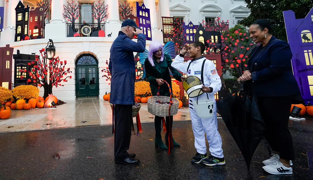 Presiden Joe Biden memberi hormat kepada seorang astronot saat dia dan Ibu Negara Jill Biden memberikan suguhan pada perayaan Halloween di South Lawn Gedung Putih, Washington, Amerika Serikat, 31 Oktober 2022. Halloween bertema "Trick-or-Treating in the President and First Lady's Neighborhood" itu tampak meriah dengan dekorasi rumah hantu di Gedung Putih. (AP Photo/Alex Brandon)