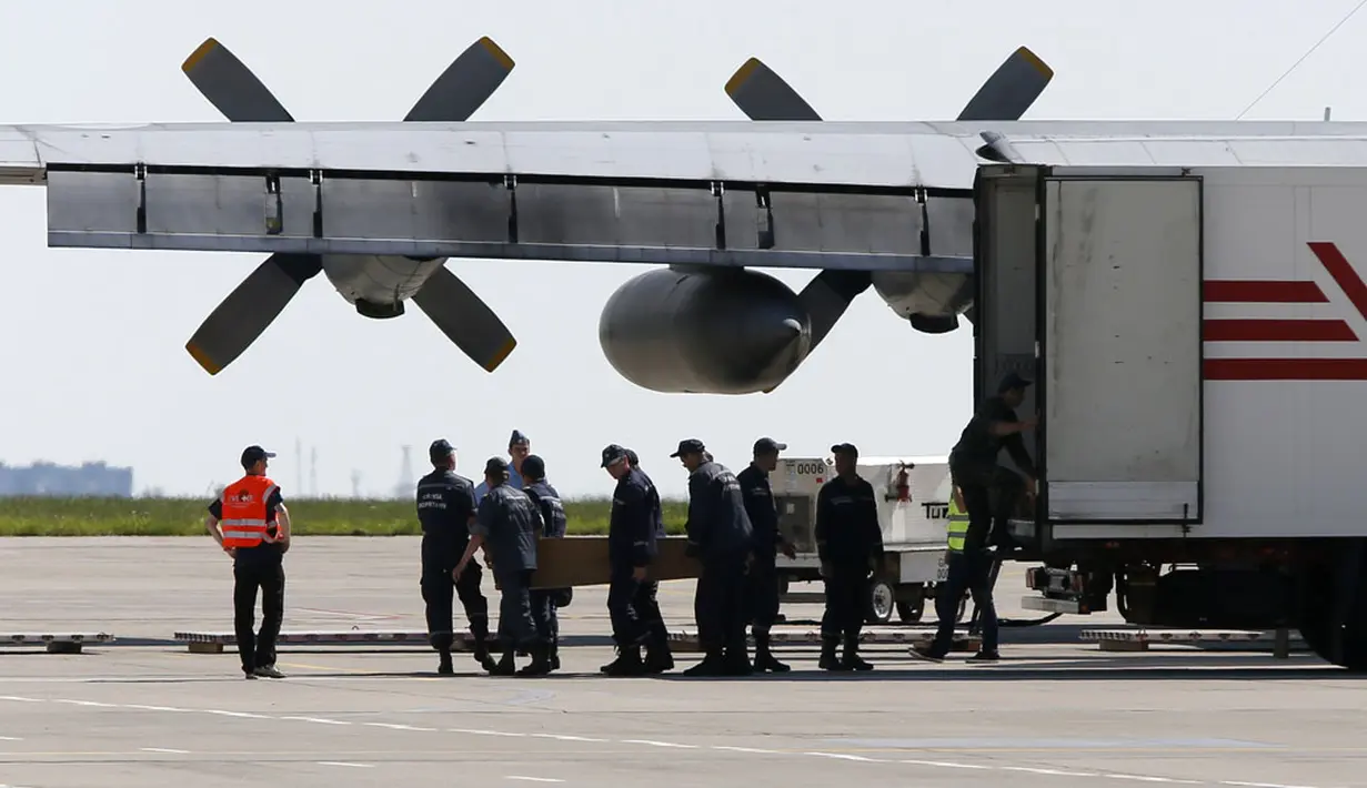 Beberapa petugas memindahkan peti jenasah korban jatuhnya pesawat Malaysia Airlines MH-17 di Bandara Kharkiv, (23/7/2014), untuk diterbangkan menuju Belanda. (REUTERS/Gleb Garanich)