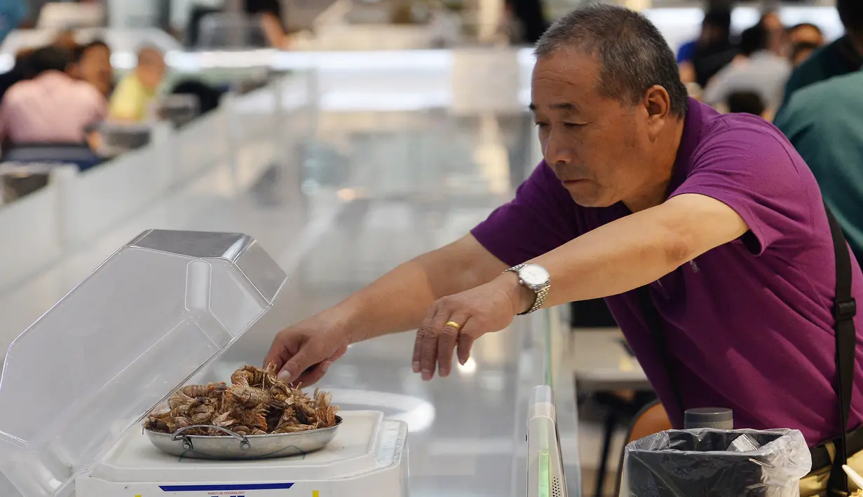Pengunjung mengambil pesanan yang diantarkan oleh robot di restoran Robot.He milik Alibaba di Shanghai, 30 Juli 2018. Robot-robot ini dipandu software yang menggunakan sistem kode QR untuk mengetahui posisi pelanggan pemesan, pesanan dan pembayaran. (AFP)