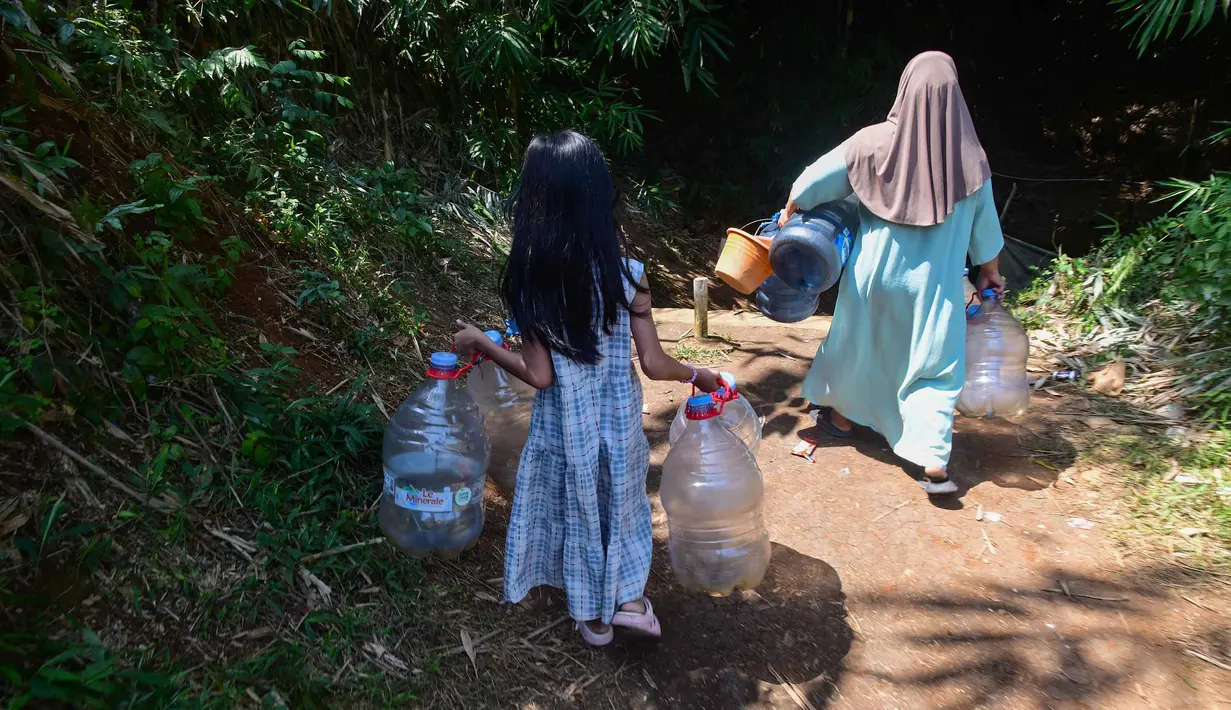 Seorang anak menemani ibunya Warga mengambir air dari satu-satunya sumber mata air di di Kampung Cijaura, Desa Cidokom, Bogor, Jawa Barat, Minggu (26/07/2026). (KLY/ Arie Basuki)