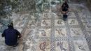 Petani Palestina Salman al-Nabahin dan putranya menemukan mosaik era Bizantium yang ditemukan di Bureij, Jalur Gaza, Palestina, 18 September 2022. Para ahli menyebutnya sebagai salah satu harta arkeologi terbesar yang pernah ditemukan di Jalur Gaza. (MOHAMMED ABED/AFP)