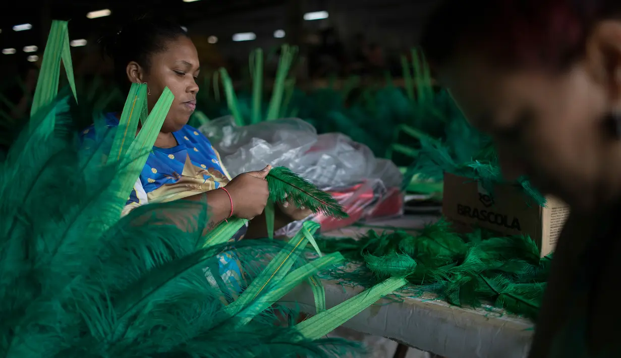Seorang wanita memotong bulu yang telah disepuh yang akan digunakan sekolah samba Paraiso do Tuiuti di Rio de Janeiro, Brasil (16/1). (AP Photo / Leo Correa)