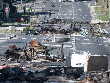 Sebuah jalan diblokir oleh puing-puing dan barang-barang yang terbakar pasca-kerusuhan semalam di distrik Magenta di Noumea, wilayah Pasifik Prancis di Kaledonia Baru, pada 18 Mei 2024. (Delphine Mayeur/AFP
