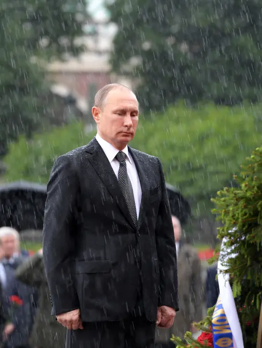 Presiden Rusia Vladimir Putin berdiri di tengah hujan selama upacara kehormatan untuk memperingati invasi Nazi Jerman pada 1941 di Benteng Kremlin, di Moskow, Kamis (22/6). (Alexei Druzhinin/Sputnik, Kremlin Pool Photo via AP)