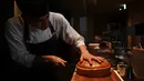 Chef dari restoran The Oak Door, Patrick Shimada menyiapkan burger raksasa di hotel Grand Hyatt Tokyo, Senin (1/4). Restoran itu membuat hamburger wagyu seukuran bola sepak yang disajikan dengan roti bertabur emas untuk merayakan penobatan kaisar baru Jepang bulan depan. (CHARLY TRIBALLEAU/AFP)