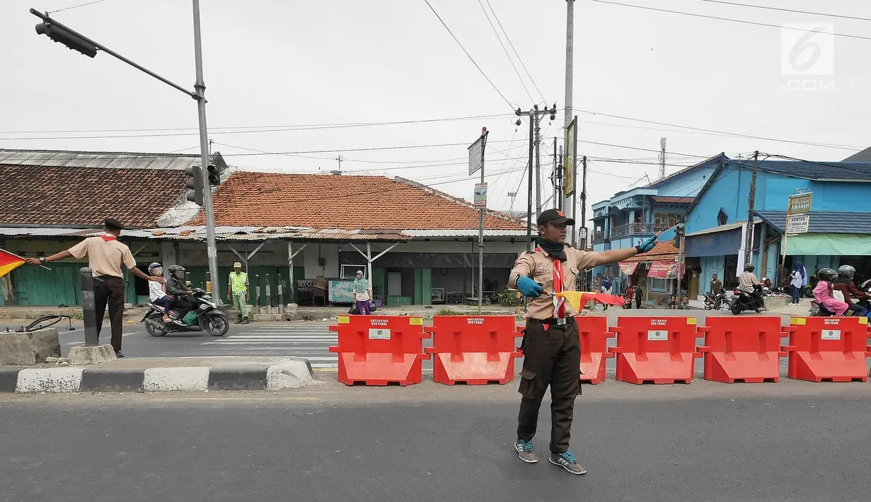 Anggota Pramuka membantu mengatur lalu lintas di jalur mudik kawasan pasar Surodadi, Tegal  Jawa Tengah, Senin (3/6/2019). Puluhan anggota Pramuka  membantu polisi mengatur lalu lintas selama arus mudik maupun arus balik. (Liputan6.com/Herman Zakharia)