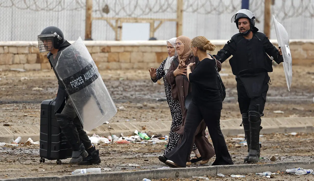 Anggota pasukan keamanan Maroko mengawal para wanita dari lokasi bentrokan dekat Fnideq, di perbatasan Maroko-Spanyol, Jumat, 31 Juli 2026. (AFP/  Abdel Majid Bziouat)