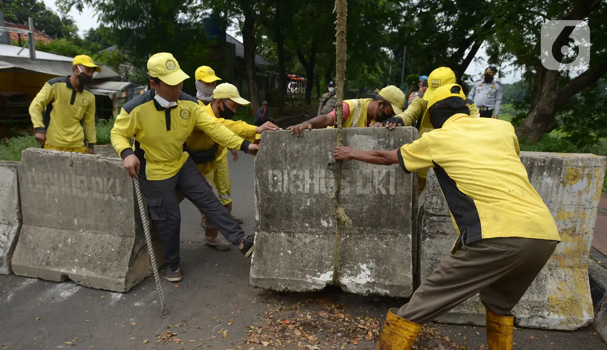 Petugas gabungan memindahkan beton pembatas di Jalur Inspeksi Kanal Banjir Timur (KBT), Cipinang, Jakarta Timur, Kamis (30/12/2021). Kawasan KBT ditutup guna mencegah kerumunan warga yang hendak merayakan malam pergantian tahun. (merdeka.com/Imam Buhori)